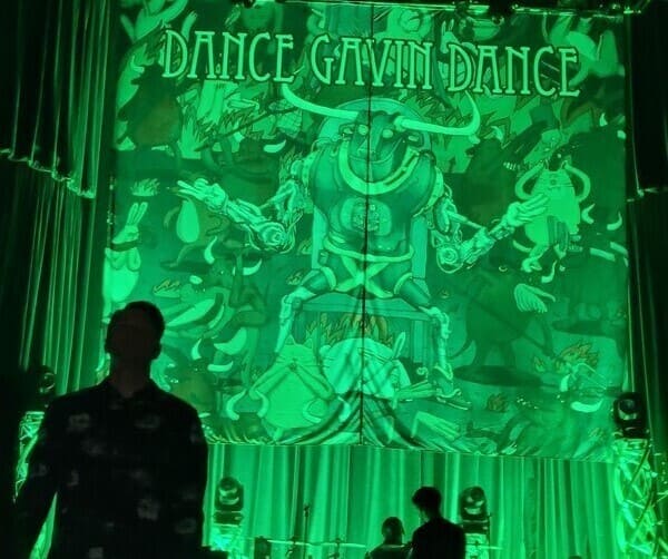 dance gavin dance banner on the stage being lit by green light